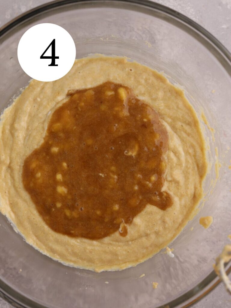 A mixing bowl with banana and sugar on top of batter.