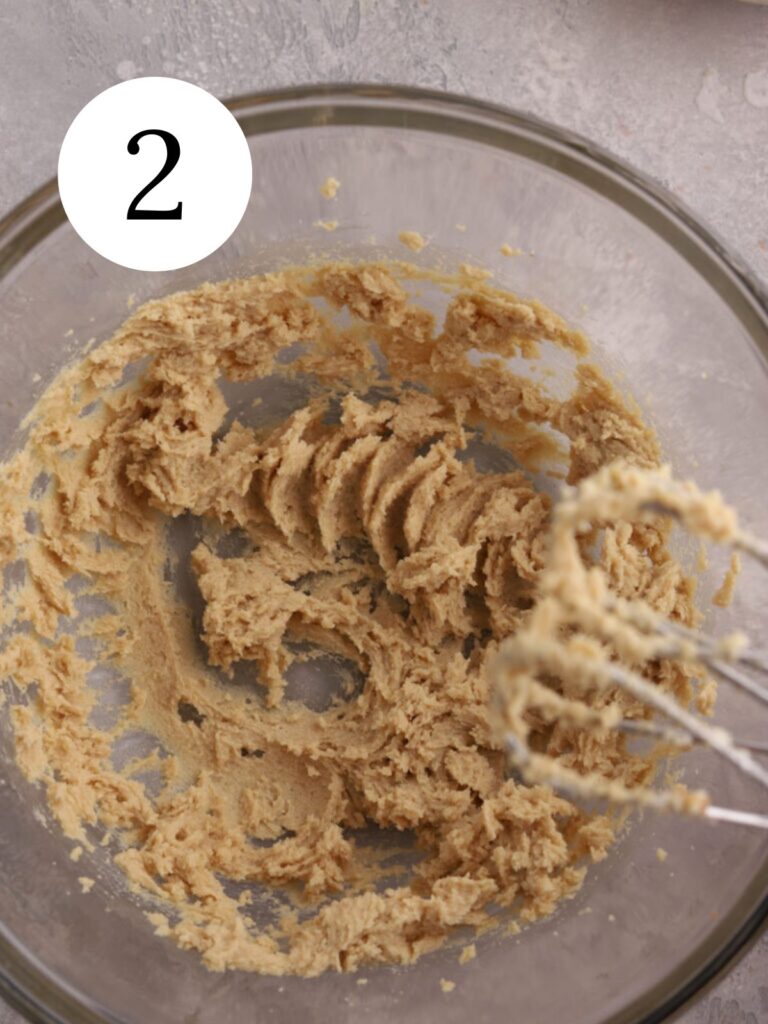 A mixing bowl with creamed butter and sugar.