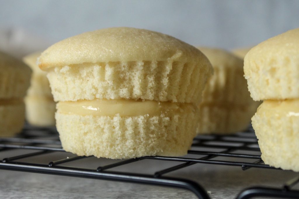 Vanilla cupcakes sliced in half with vanilla cream in the middles. 