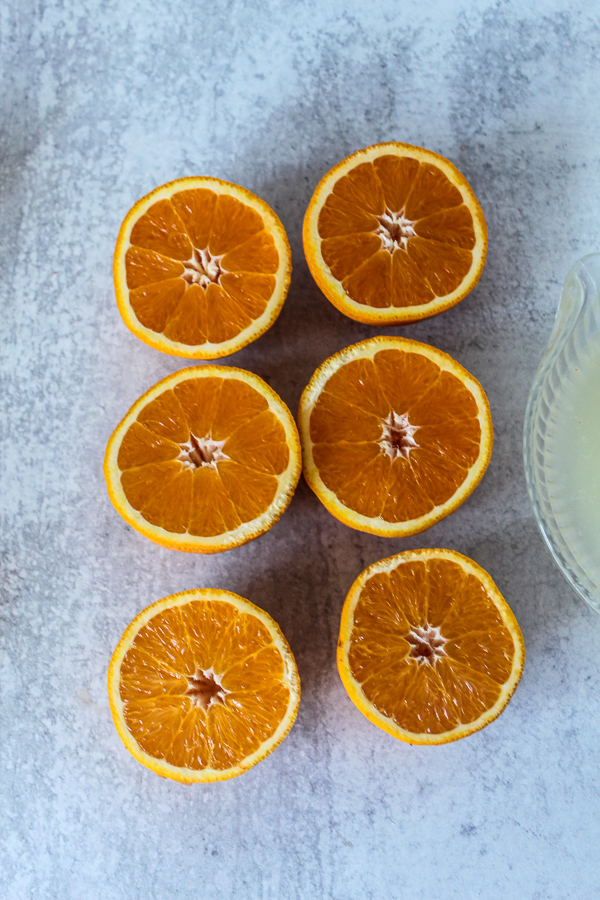 overhead view of six orange slices with lemon juice in a strainer next to them
