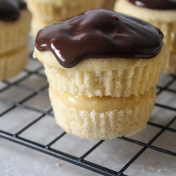 Boston cream pie cupcakes on a cooling rack.