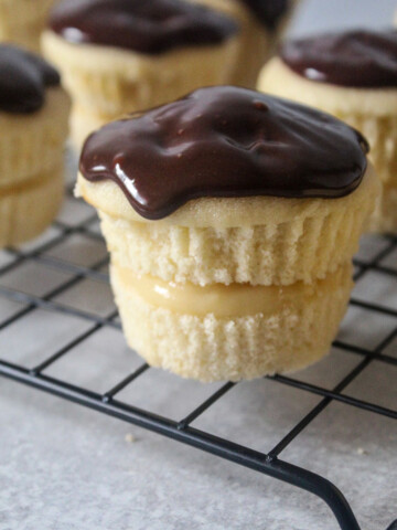 Boston cream pie cupcakes on a cooling rack.