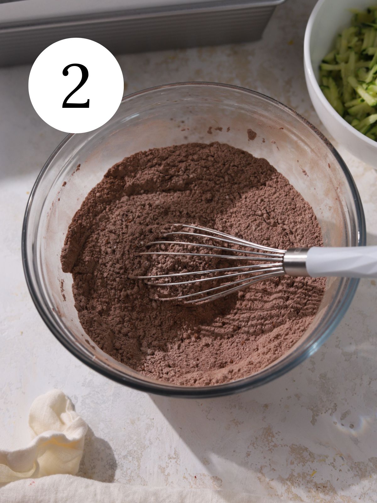 Cocoa powder and other dry ingredients in a bowl with a whisk.