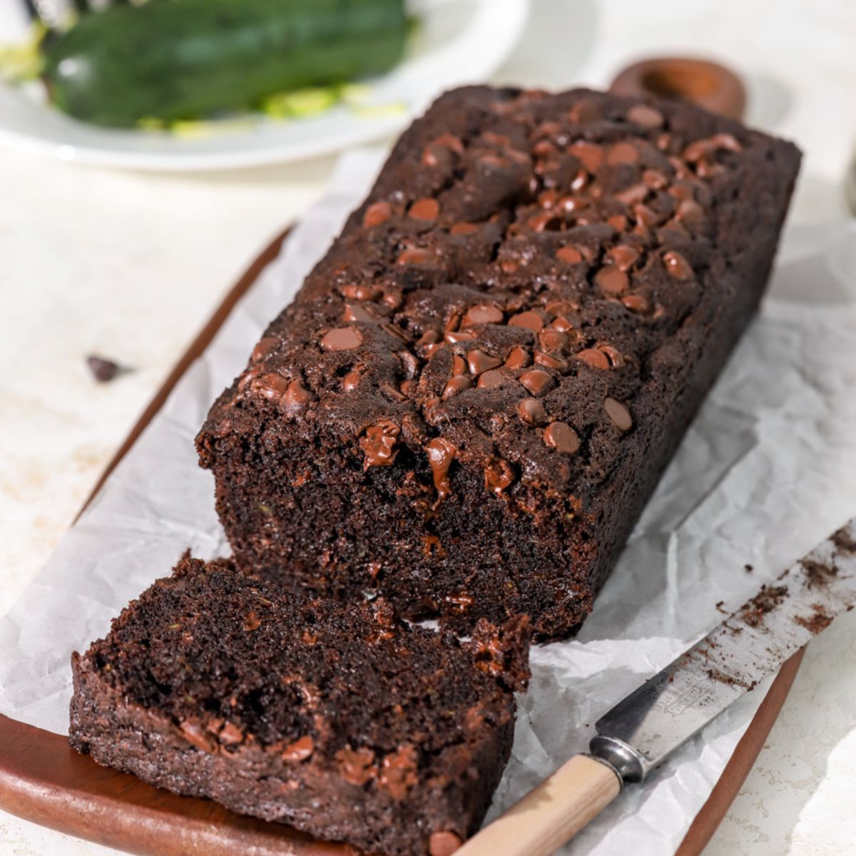 Chocolate zucchini bread being sliced with a knife next to it.