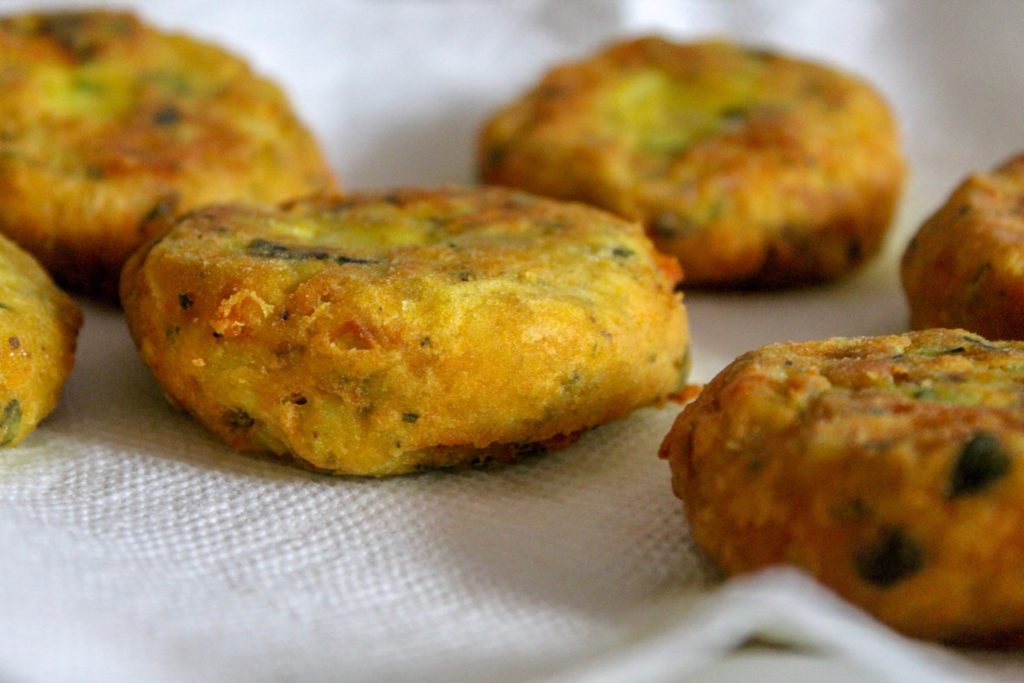 golden potato fritters with herbs on paper towels 