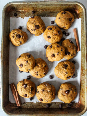 A batch of pumpkin cookies with chocolate chips on a baking sheet.