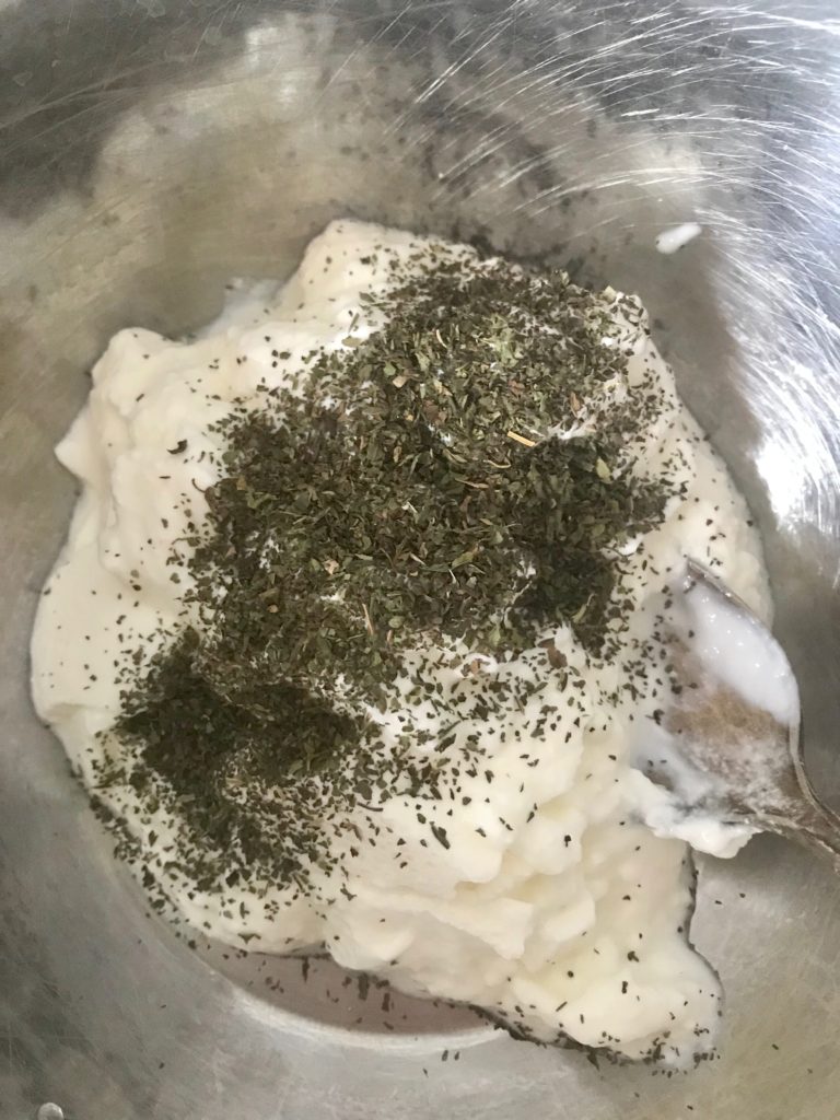 yogurt with dried parsley and mint on top of it in a bowl
