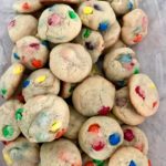a big batch of m&m cookies in a clear tupperware container