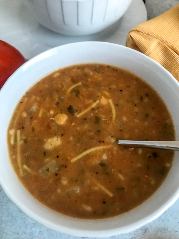 a delicious bowl of harira soup with pasta, bits of onion, chick peas and parsley and pureed tomatoes