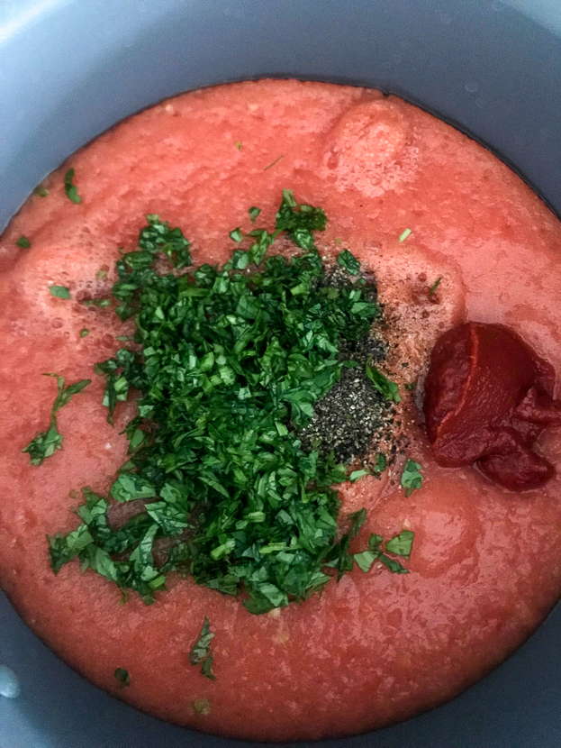 A pot full of freshly chopped parsley, pepper, pureed tomatoes and tomato concentrate.