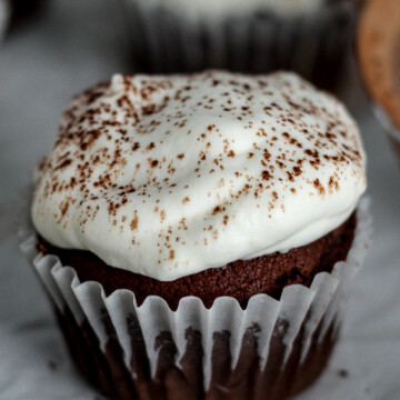 a chocolate gingerbread cupcake with a dollop of whipped cream sprinkled with cocoa