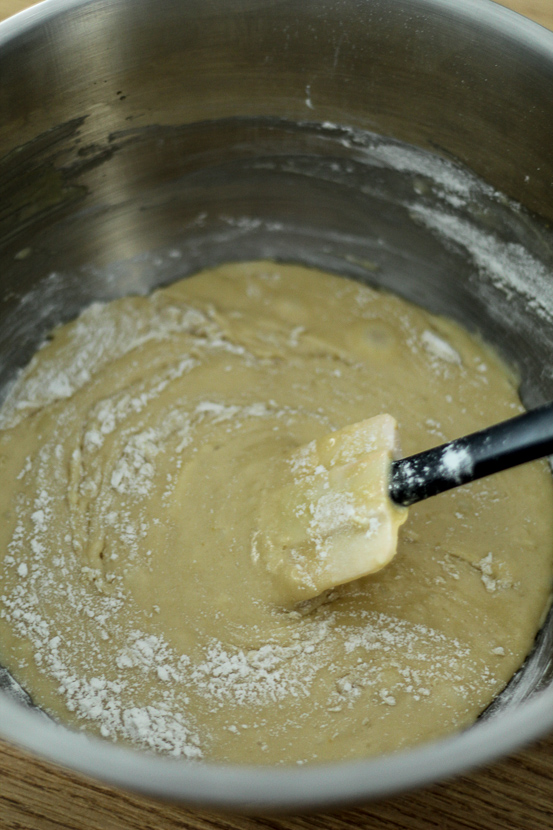 A spatula stirring a gorgeous white chocolate cake batter in a mixing bowl.