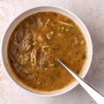 A bowl of Moroccan harira soup with a spoon in it.