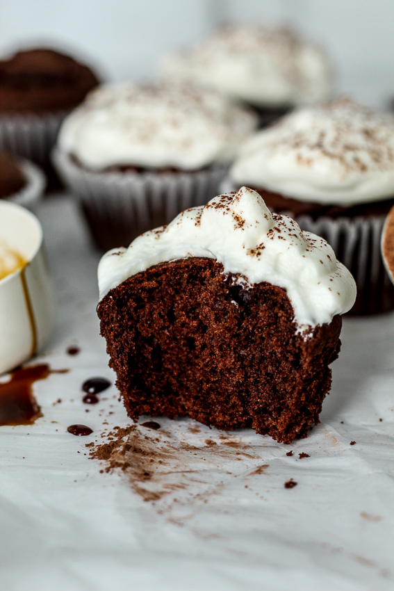 a chocolate gingerbread cupcake with a dollop of whipped cream sprinkled with cocoa and molasses and cocoa on the counter 
