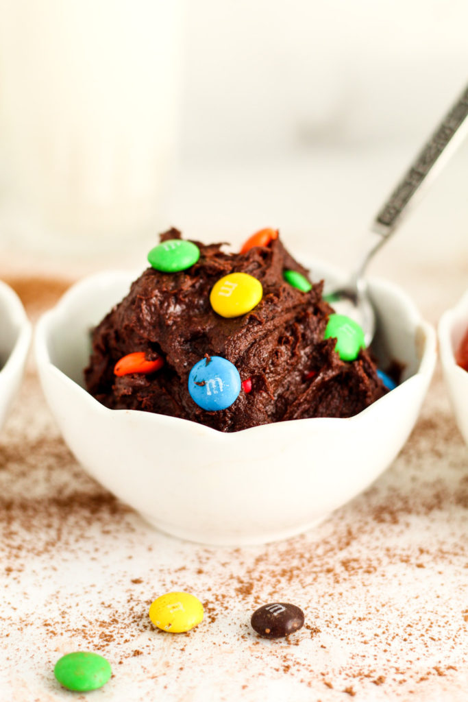 Chocolatey brownie batter in a bowl with M&Ms. 