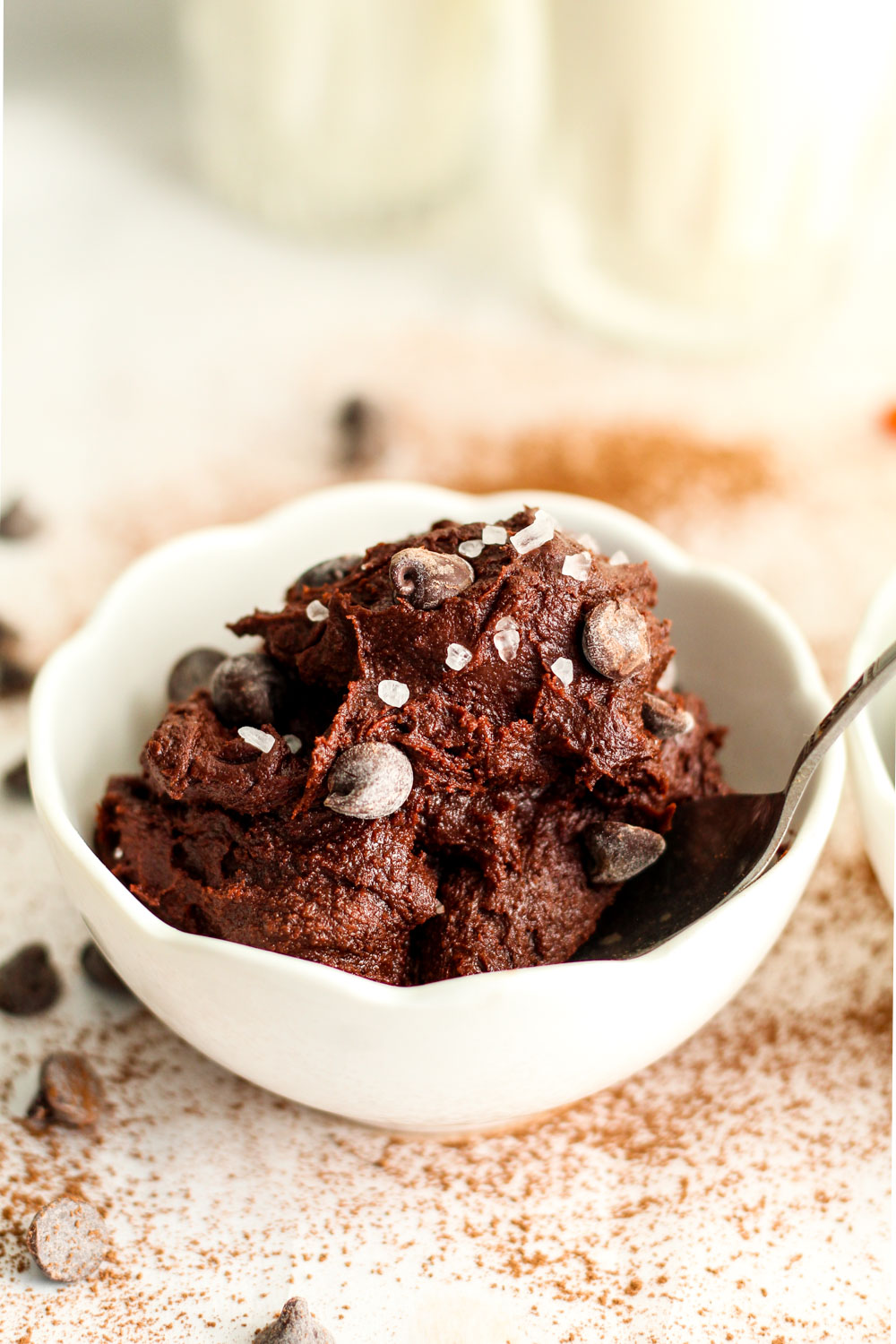 A small white bowl with brownie batter and chocolate chips in it.