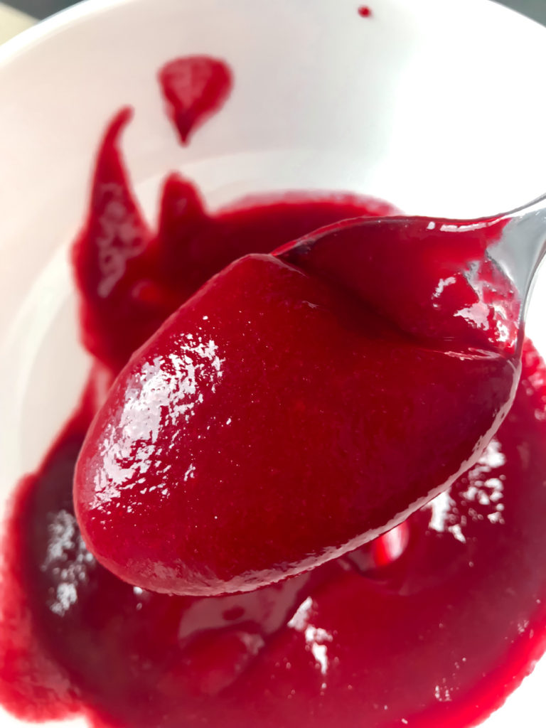 A spoonful of creamy, bright red homemade raspberry sauce. 