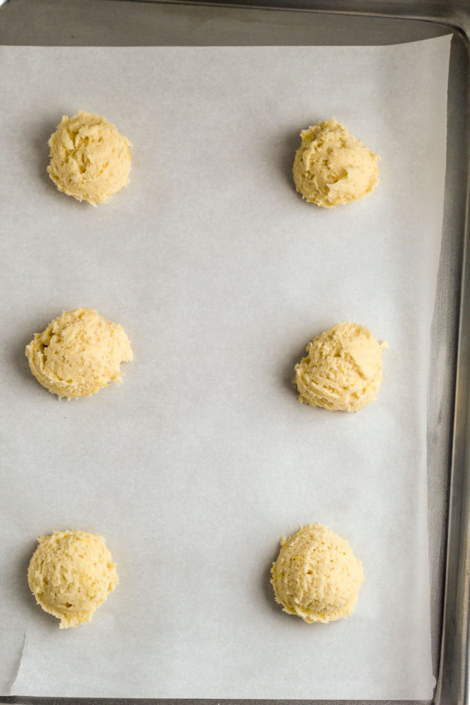 Lemon cookie dough in balls on a baking sheet lined with parchment paper.