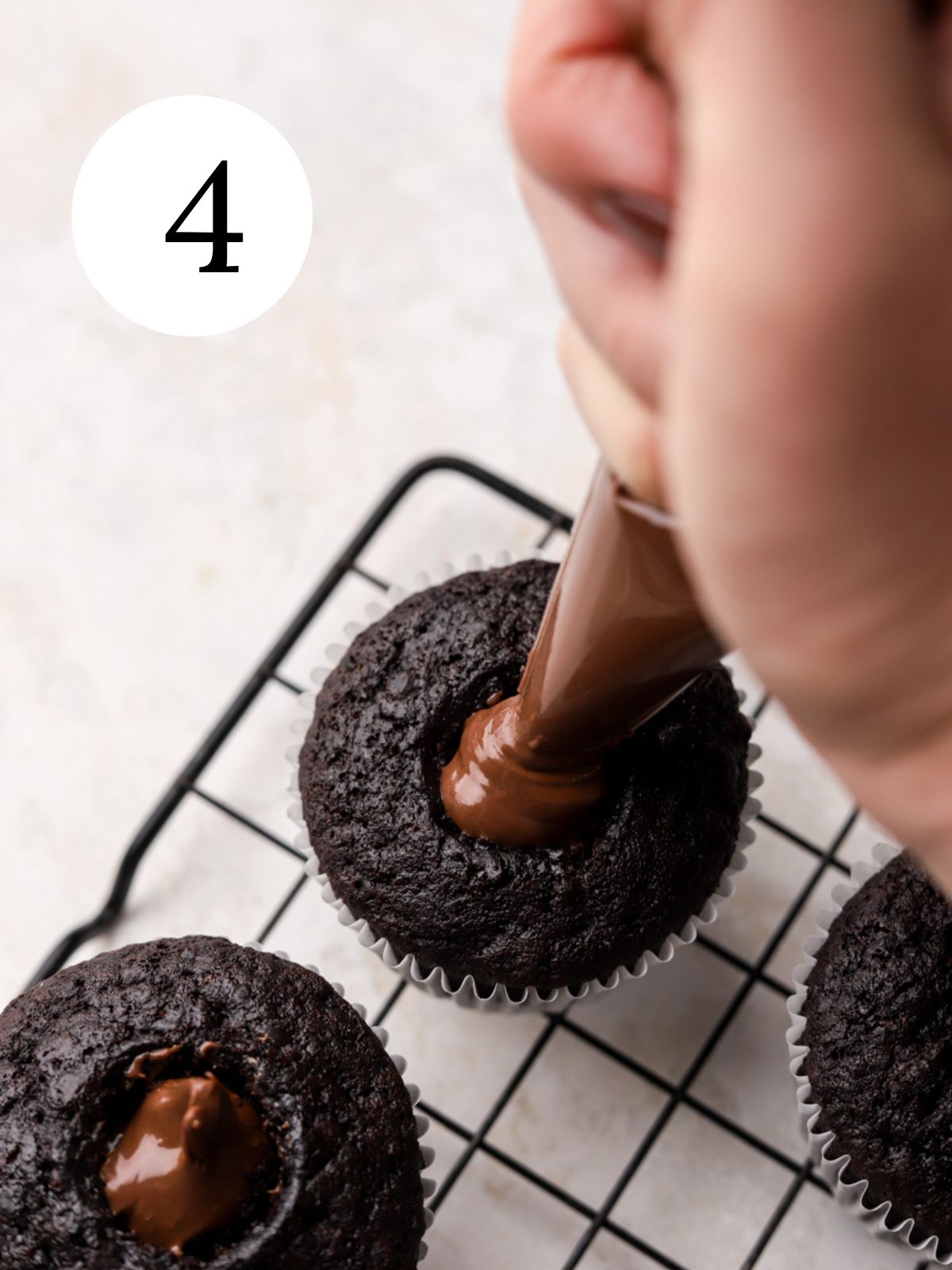 A chocolate cupcake with Nutella being piped in the middle.