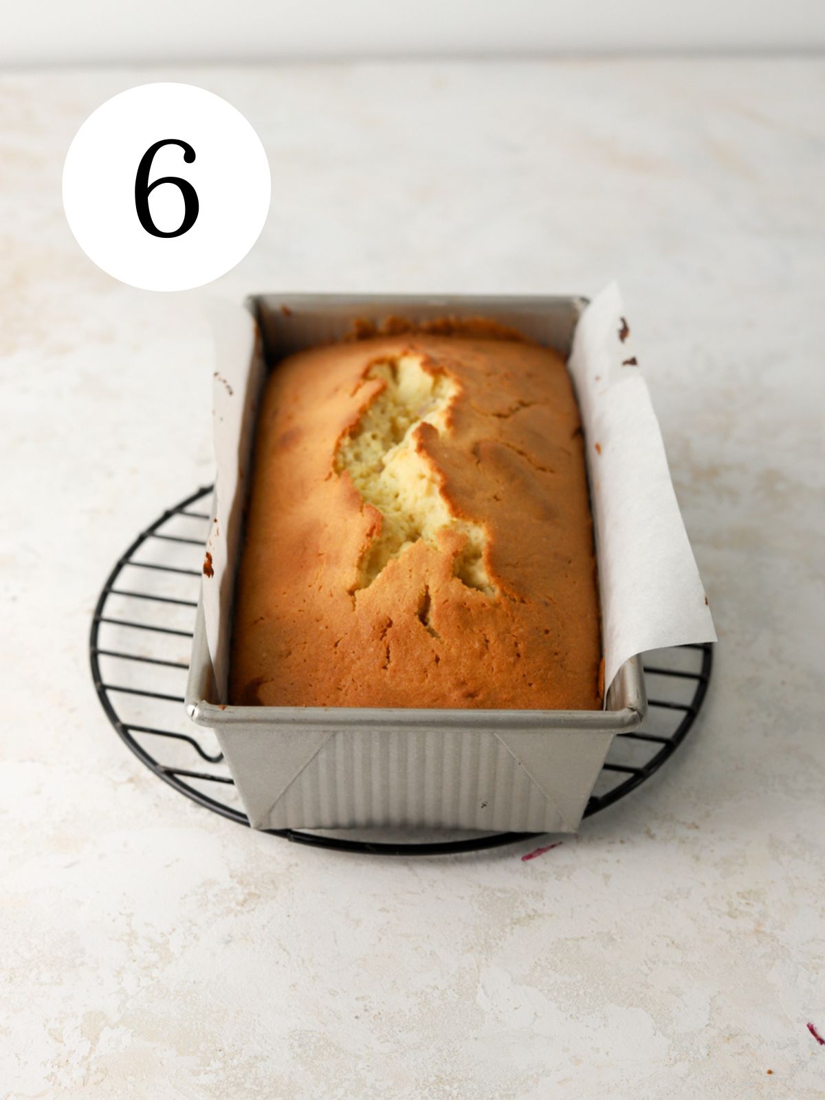 A pound cake in a pan on a round wire rack.