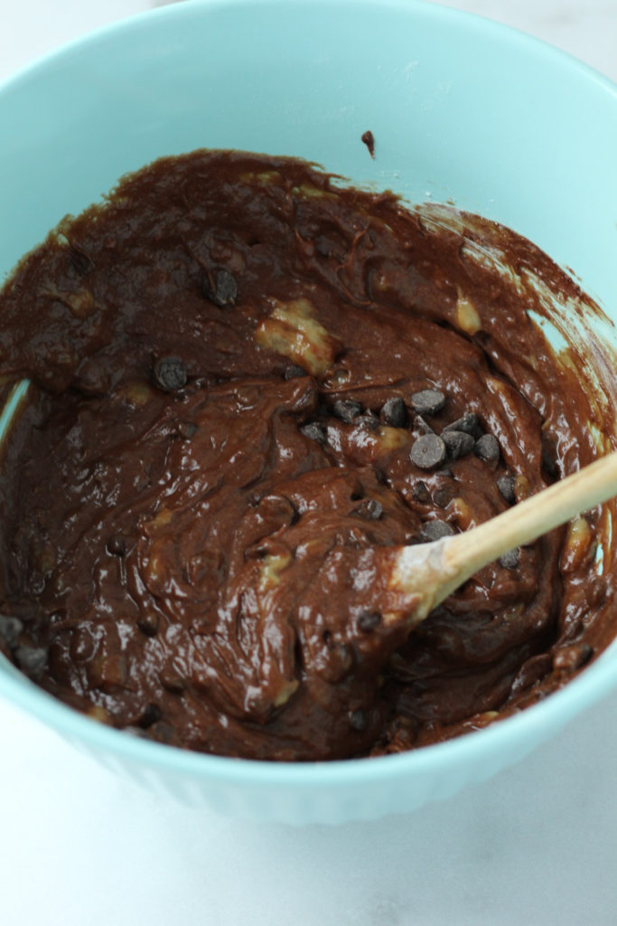 Brownie batter with chocolate chips and mashed bananas in a mixing bowl.