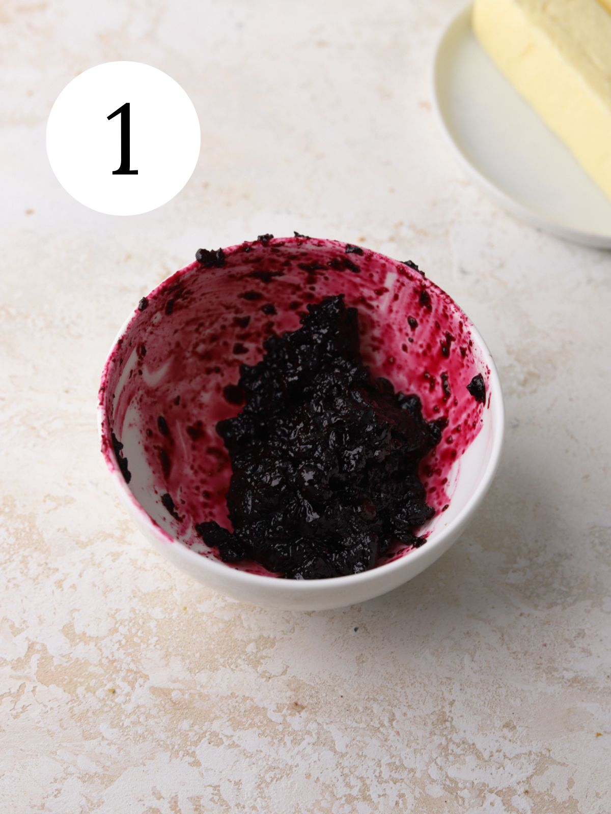 A small white bowl with blueberry jam.