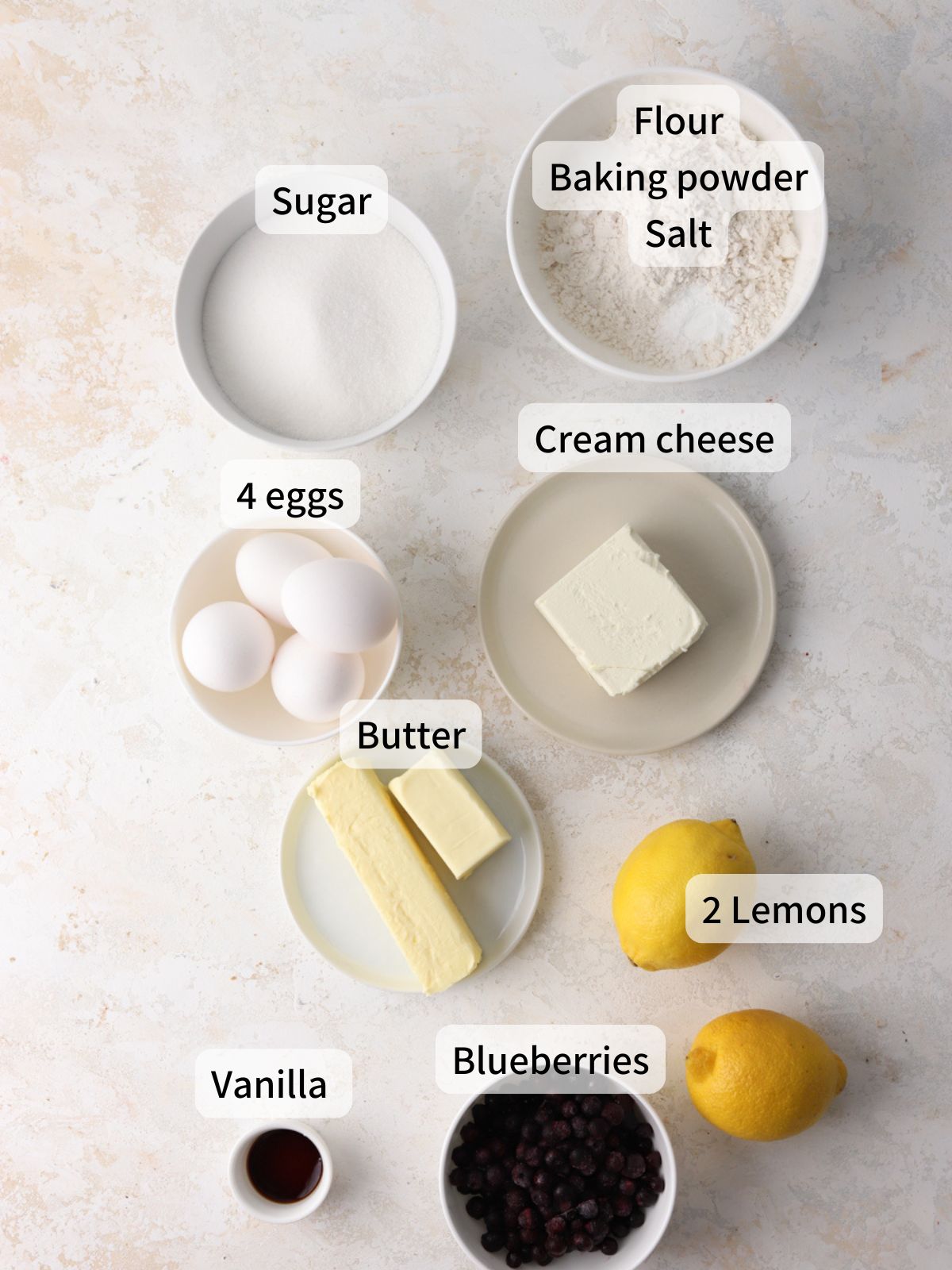 Labeled ingredients needed to make blueberry cream cheese pound cake laid out on a table.