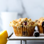 A blueberry muffin on a rack with a lemon next to it.