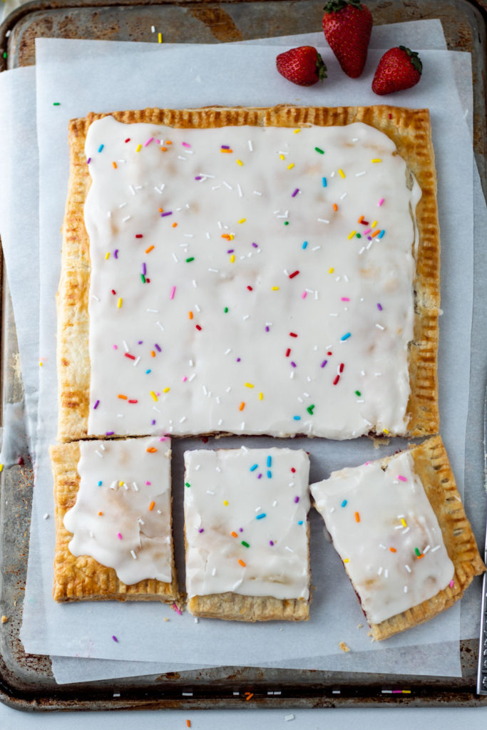 A giant homemade strawberry pop tart with icing and sprinkles on top!
