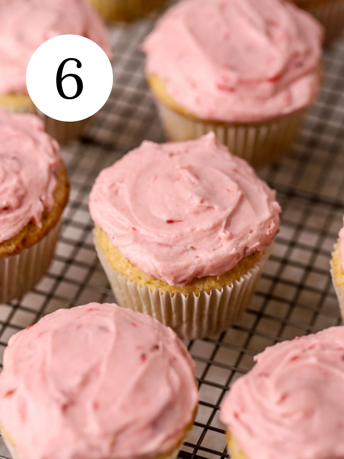 Strawberry frosted cupcakes on a wire rack.