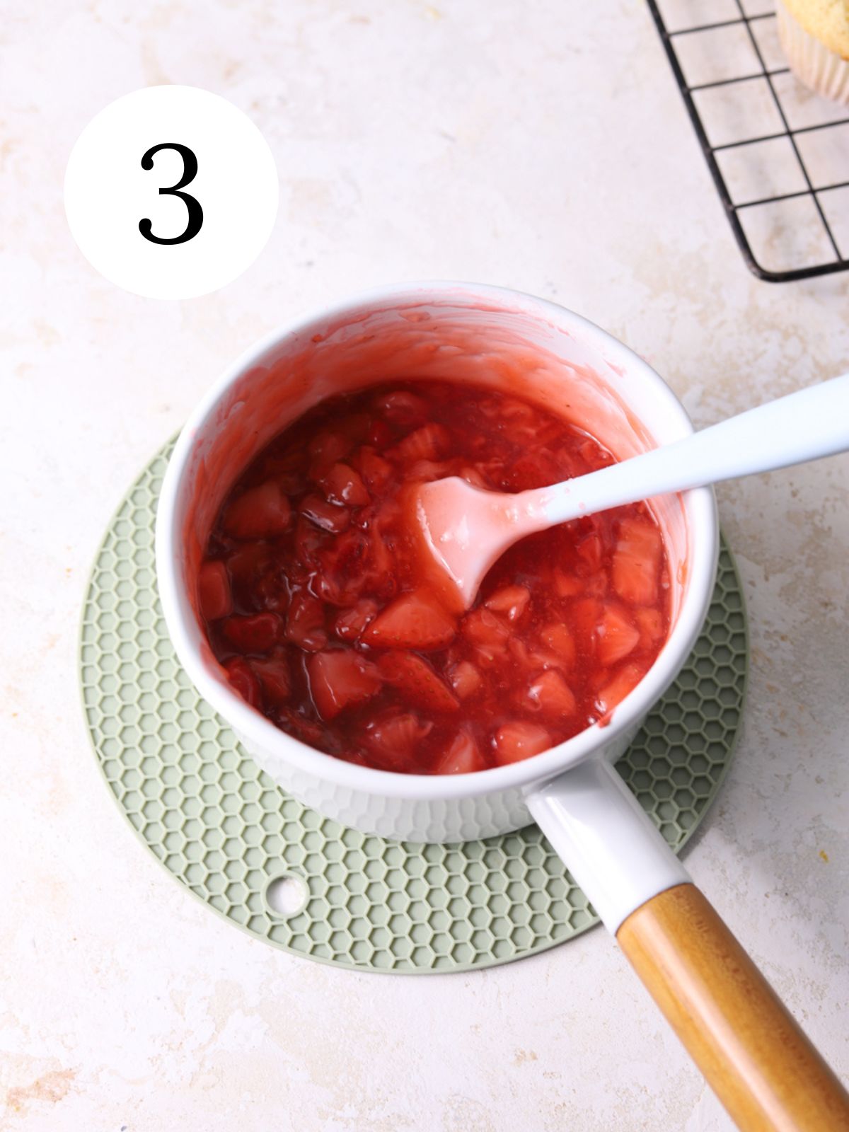 Strawberry sauce in a saucepan with a spatula in it.