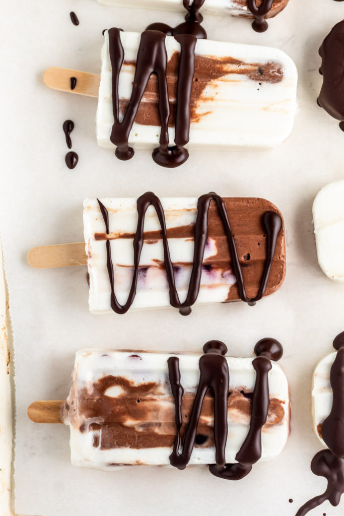 Healthy chocolate and vanilla yogurt popsicles with cherries and drizzled with melted chocolate. 