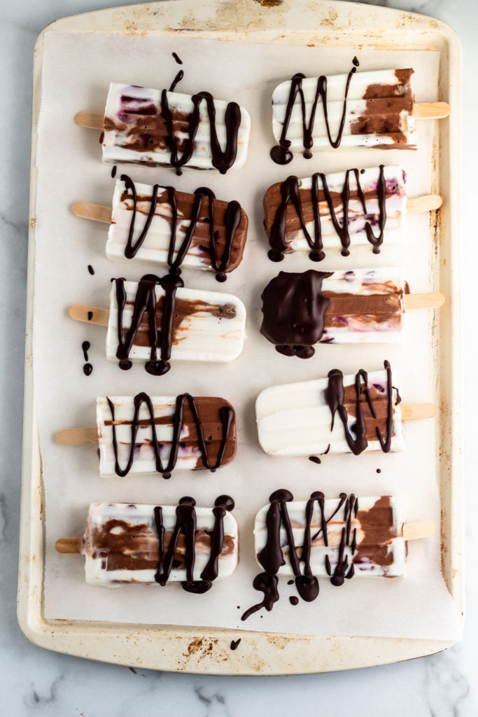 A tray with delicious yogurt chocolate cherry popsicles drizzled with dark chocolate. 