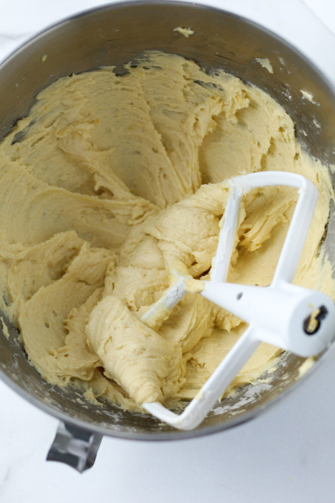 Yellow lemon cookie batter in a mixing bowl with a paddle attachment. 