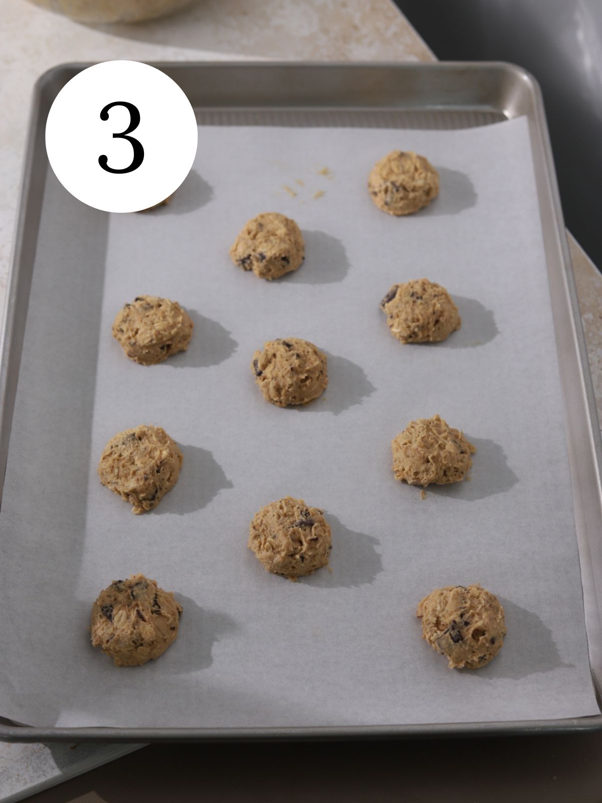 Peanut butter chocolate cookie dough balls on a baking sheet with parchment paper.