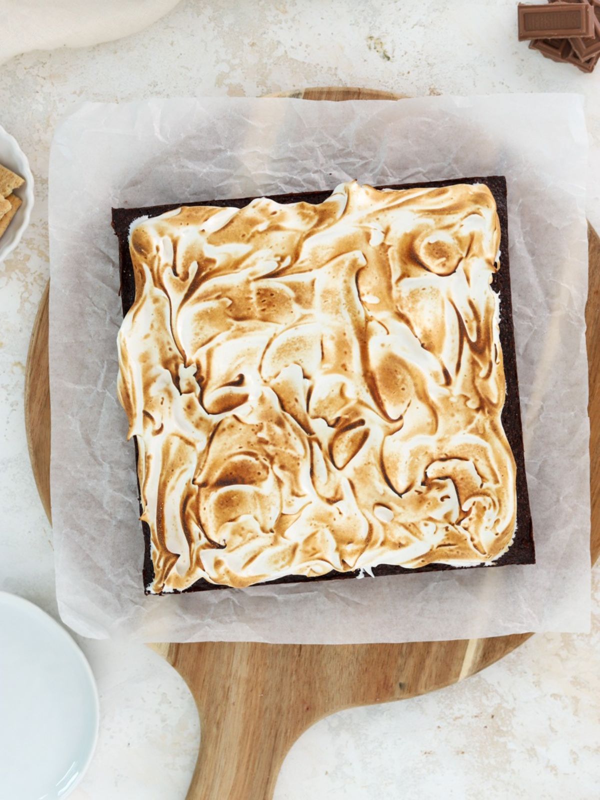 Brownies topped with toasted meringue on parchment paper.