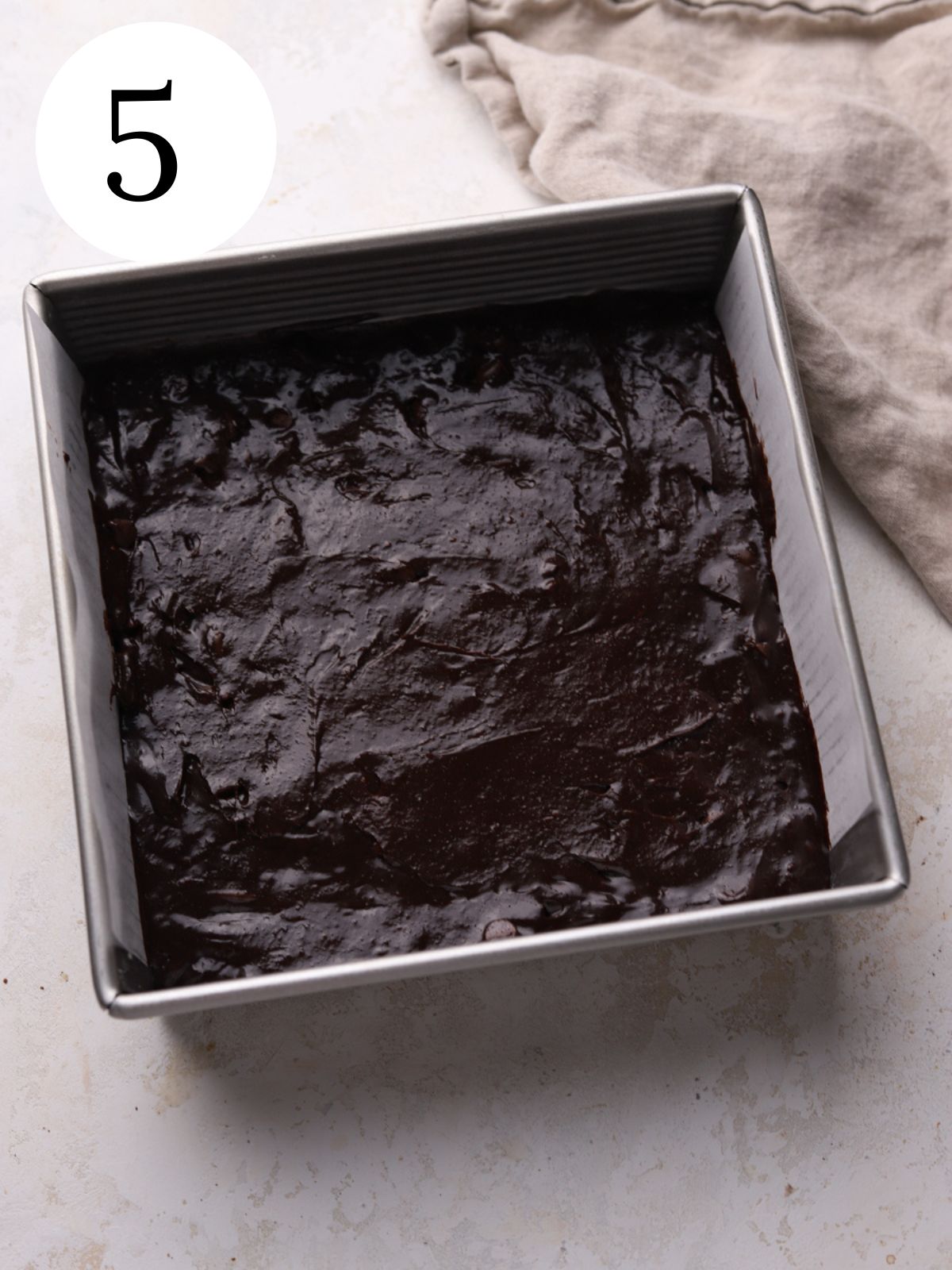 Brownie batter spread into a square pan. 
