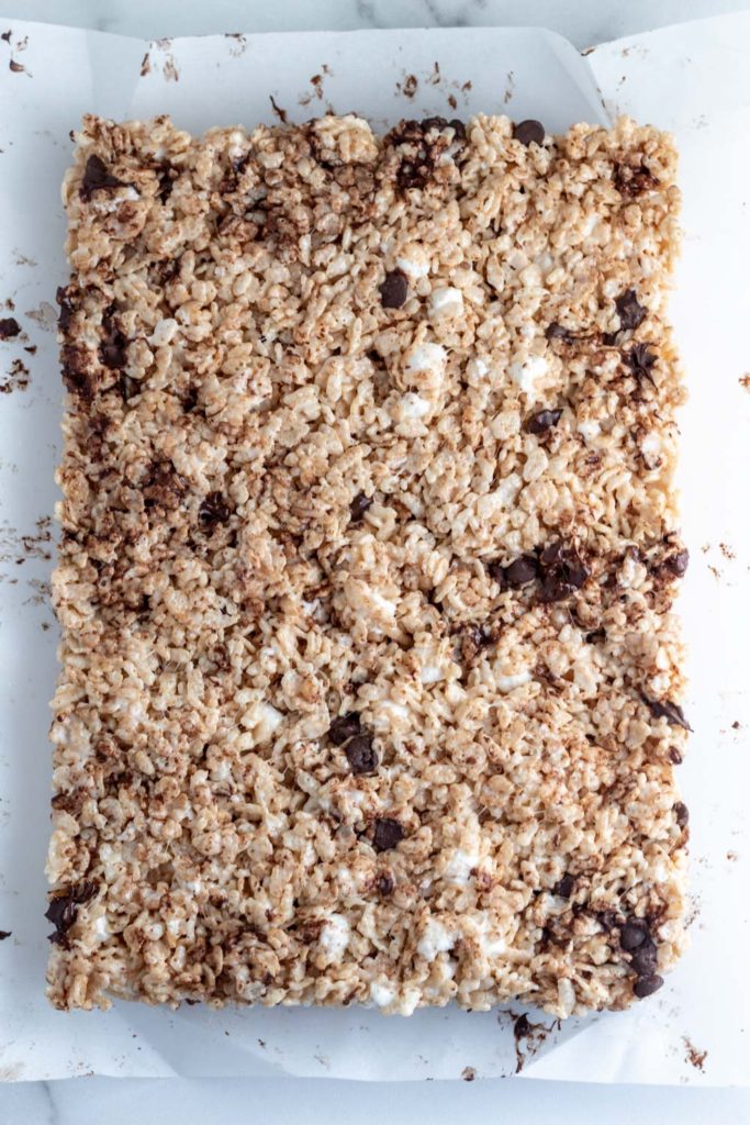 A batch of chocolate covered rice krispie treats on parchment paper. 