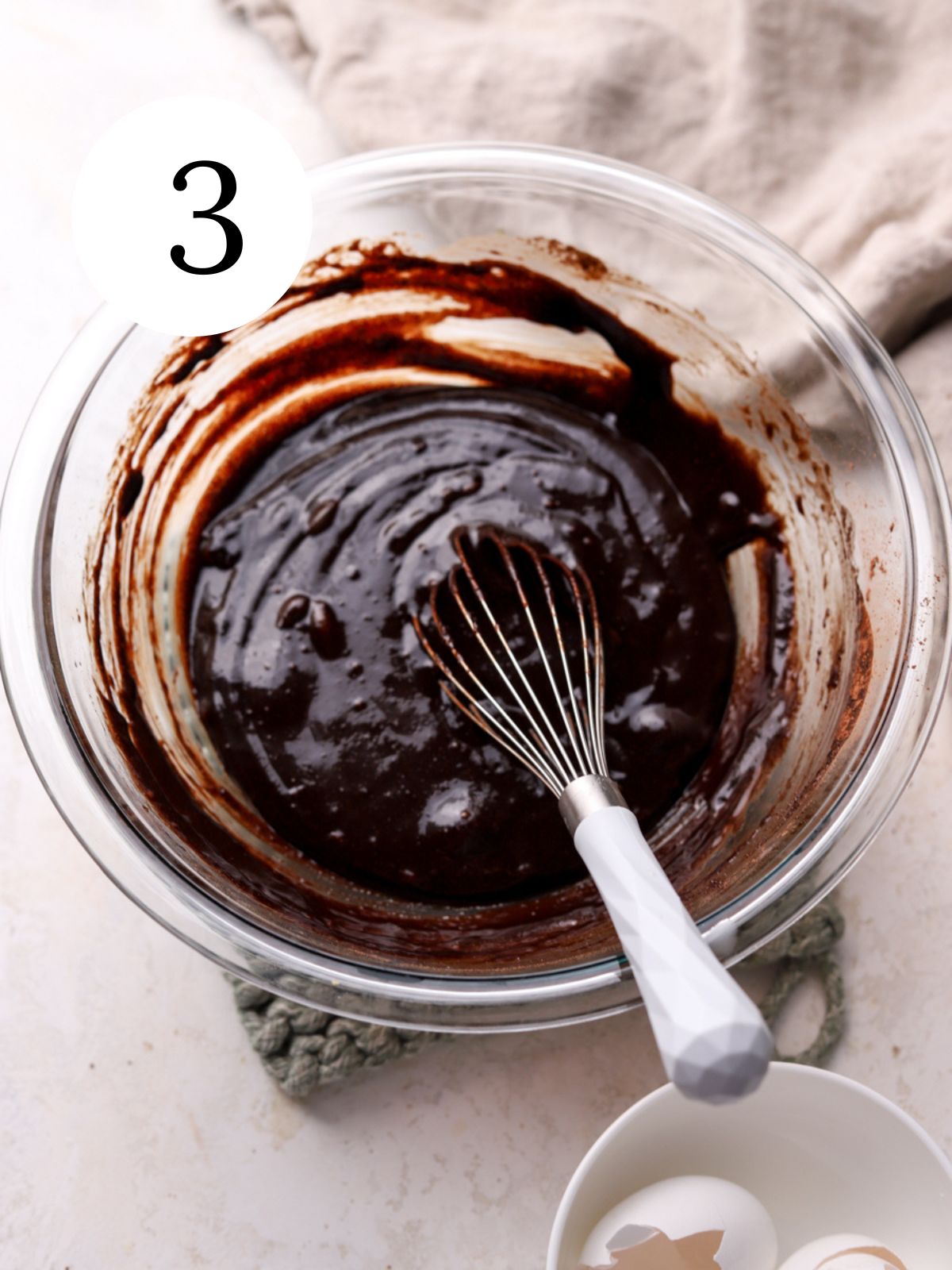 A mixing bowl with brownie batter being whisked together. 