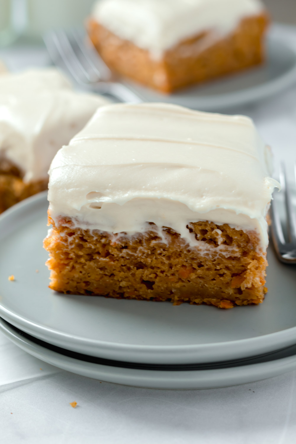 A piece of pumpkin carrot cake on a plate with a fork. 