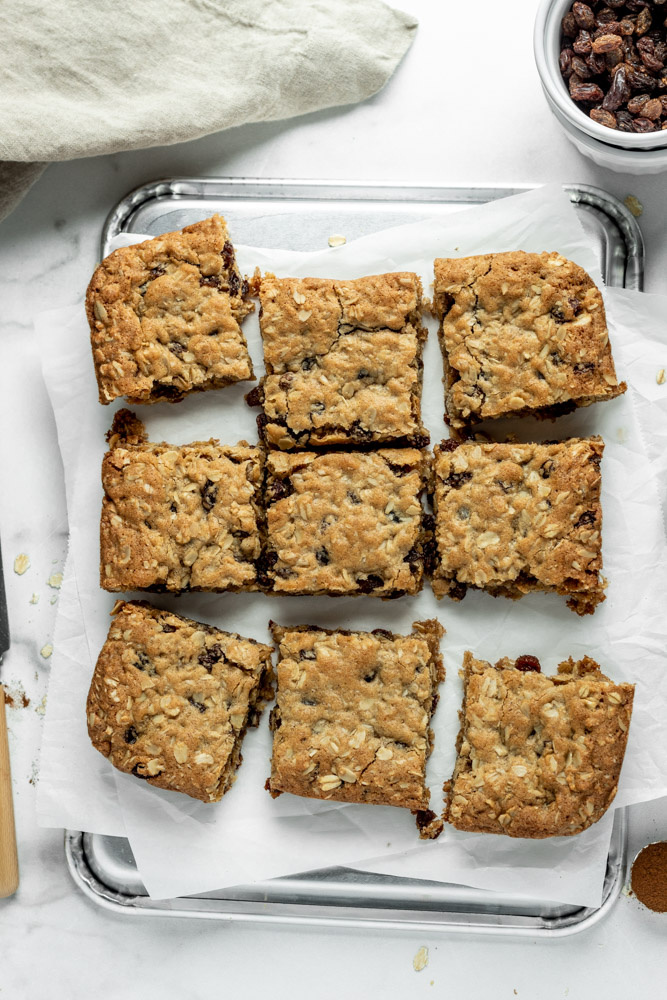 A batch of oatmeal raisin cookie bars sliced into squares on a sheet pan.