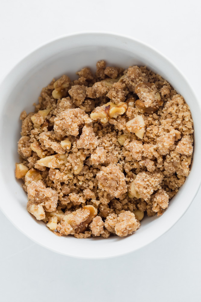 Crumbly buttery brown sugar maple walnut crumble in a white bowl. 