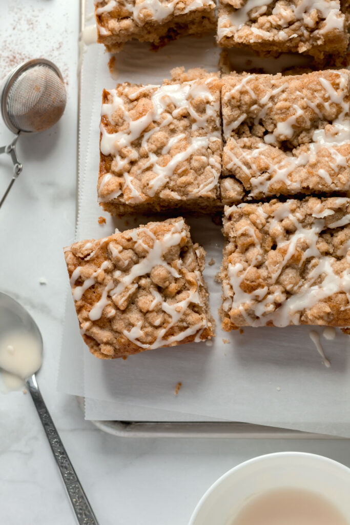 Thick slices of coffee cake topped with apple cider icing and a spoon nearby.
