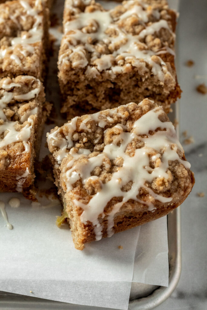 A close up of apple coffee cake pieces topped with thick streusel and sticky apple cider glaze. 
