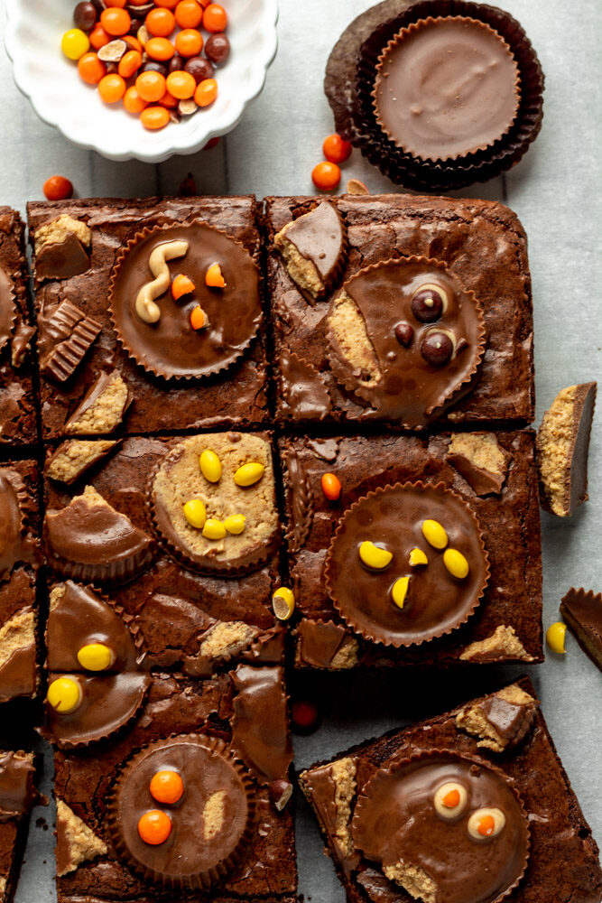 A batch of brownies sliced into big squares and topped with peanut butter cups. 