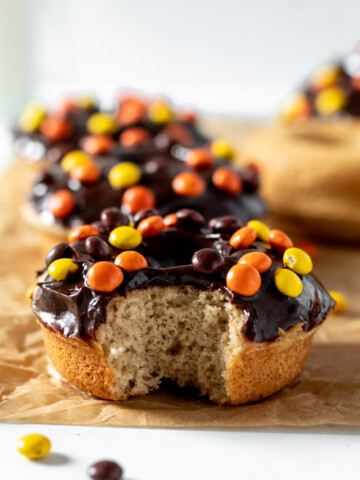 peanut butter donut covered with chocolate and reese's pieces with a bite in it.