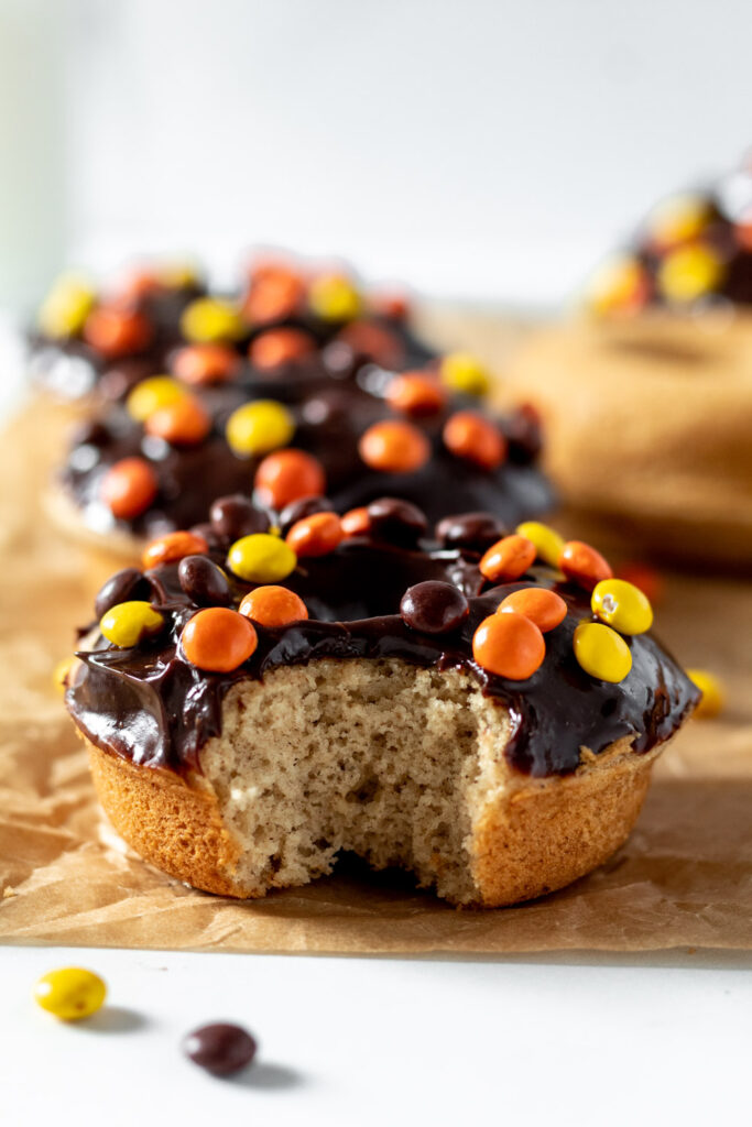 peanut butter donut covered with chocolate and reese's pieces with a bite in it. 