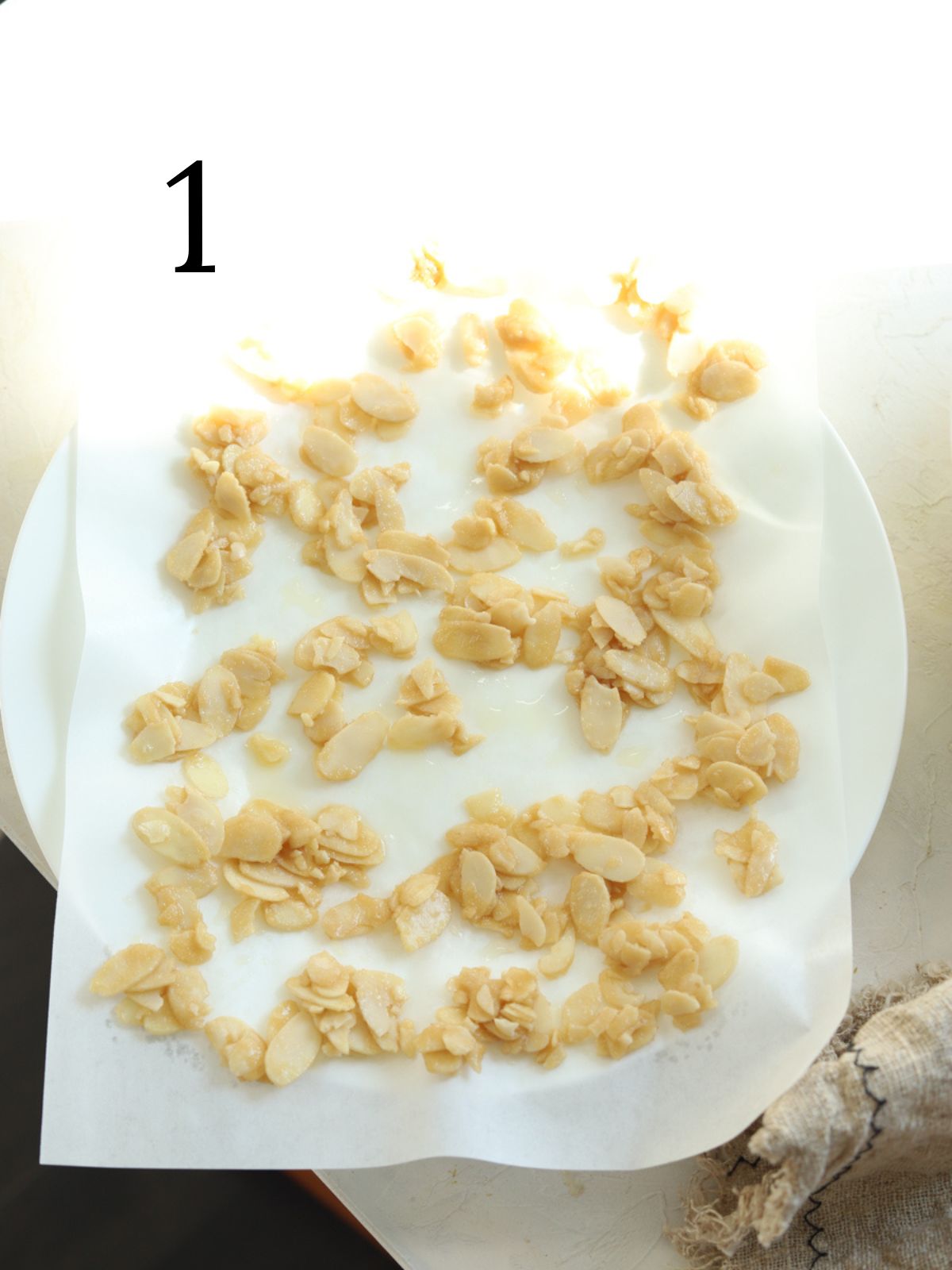 Almond clusters on a sheet of parchment paper on a white plate.