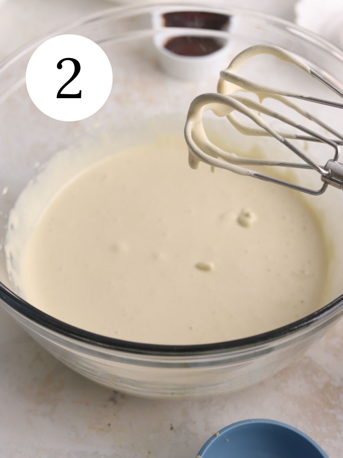 A large glass bowl with eggs and sugar mixed together with a mixer.