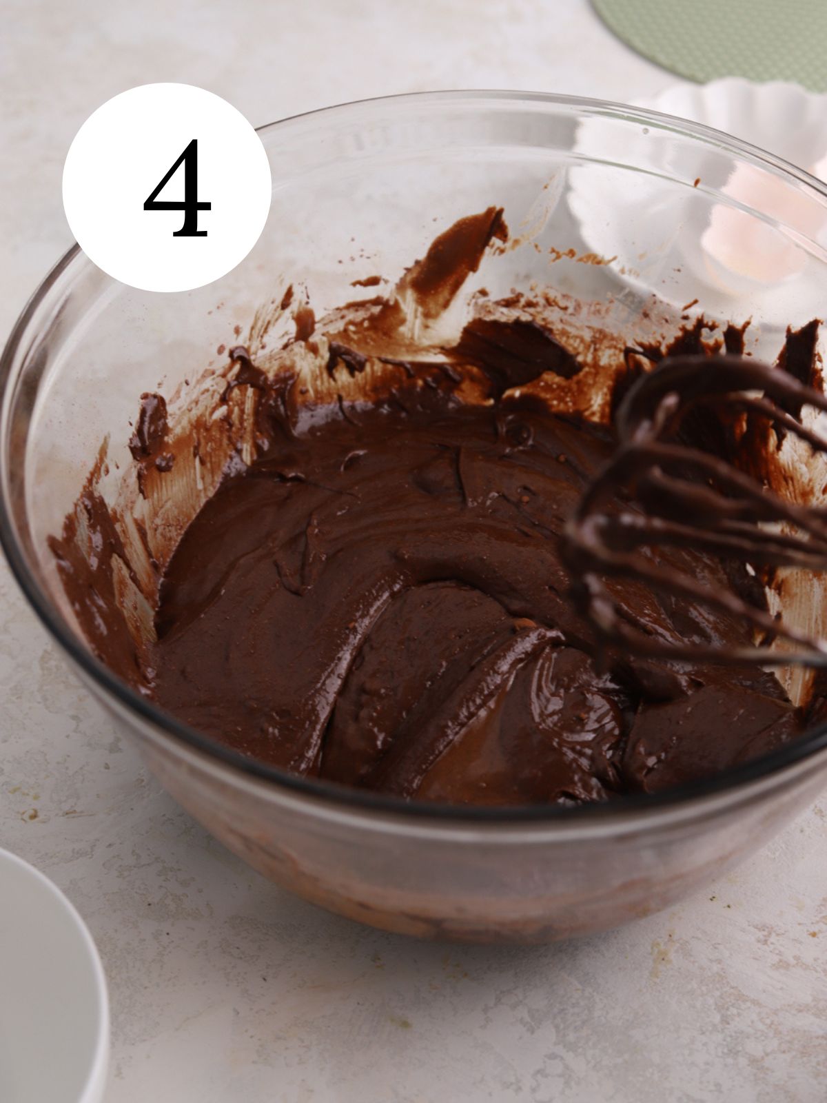 A glass bowl with brownie batter mixed together. 